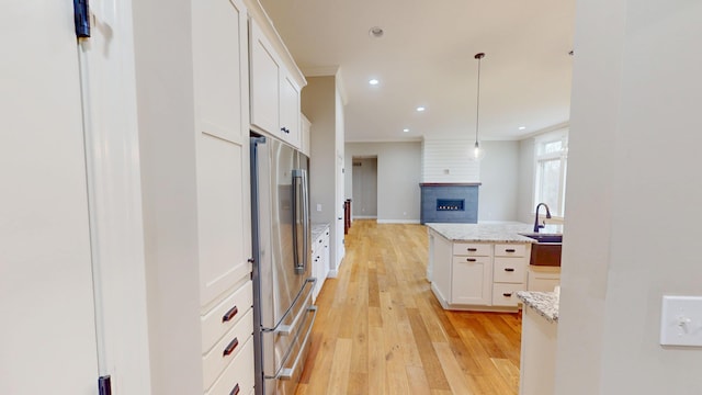 kitchen featuring ornamental molding, open floor plan, a large fireplace, white cabinets, and stainless steel fridge