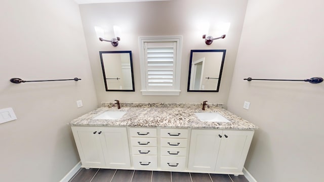 bathroom with double vanity, baseboards, and a sink