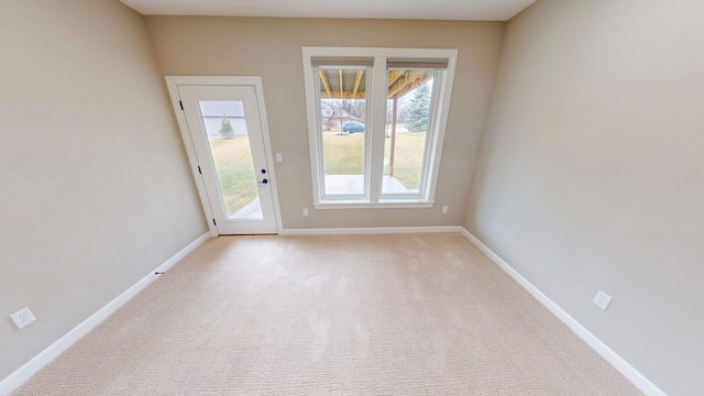 doorway with baseboards and light colored carpet