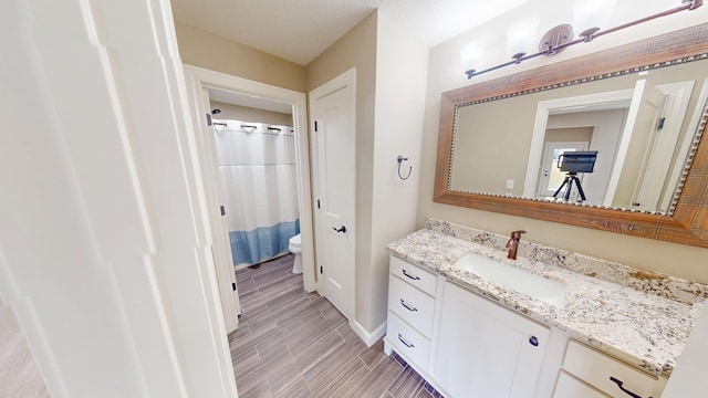 full bath with wood finish floors, baseboards, vanity, and toilet