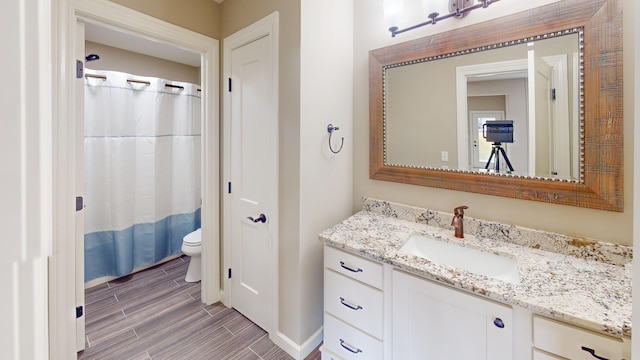 bathroom with toilet, wood finish floors, and vanity