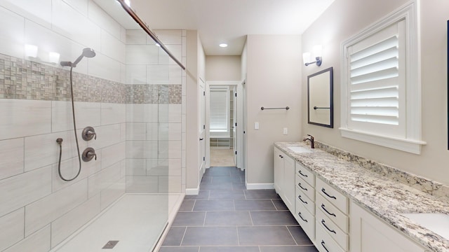 full bathroom with a sink, a shower stall, baseboards, and double vanity