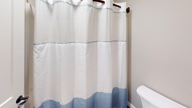 full bath with a shower with shower curtain and toilet