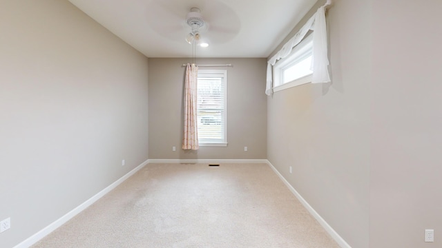 empty room featuring light colored carpet, ceiling fan, and baseboards