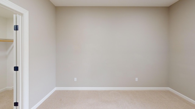 spare room with baseboards and light colored carpet