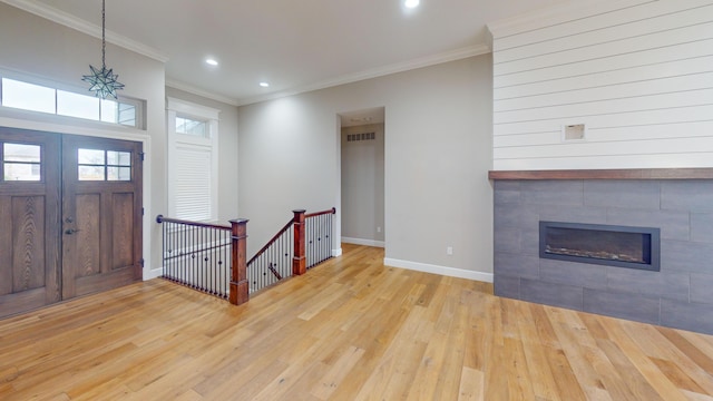 entrance foyer featuring crown molding, recessed lighting, a tiled fireplace, wood finished floors, and baseboards