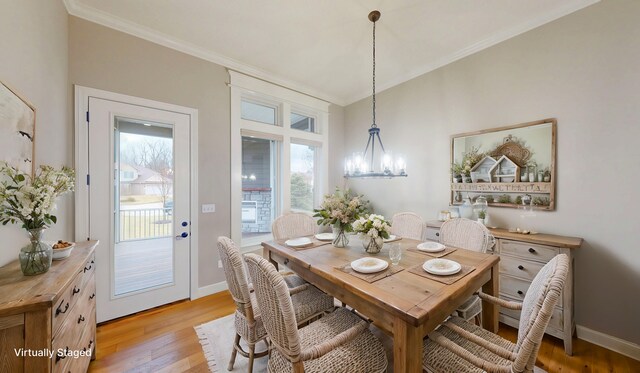 dining area with a chandelier, light wood-style floors, baseboards, and crown molding