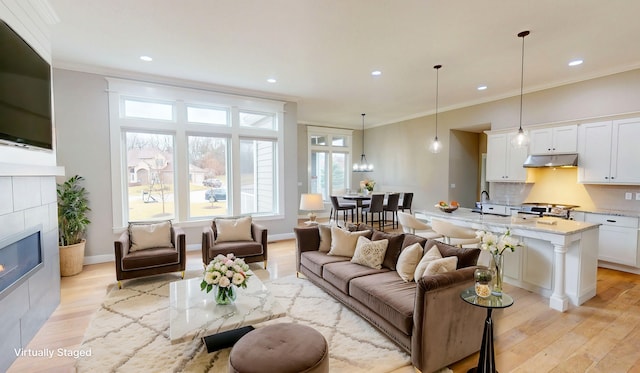 living room with ornamental molding, light wood-type flooring, a fireplace, and recessed lighting