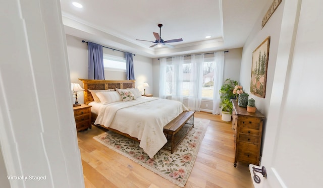 bedroom with light wood finished floors, multiple windows, a raised ceiling, and recessed lighting