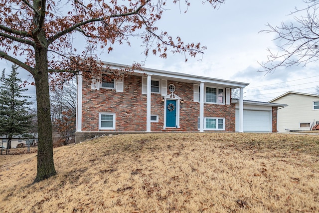 split foyer home featuring a garage, brick siding, and a front lawn