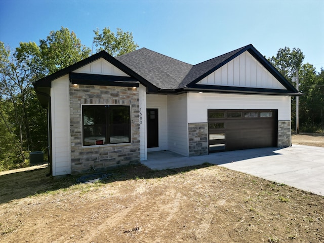 view of front of house featuring a garage, a shingled roof, driveway, stone siding, and board and batten siding