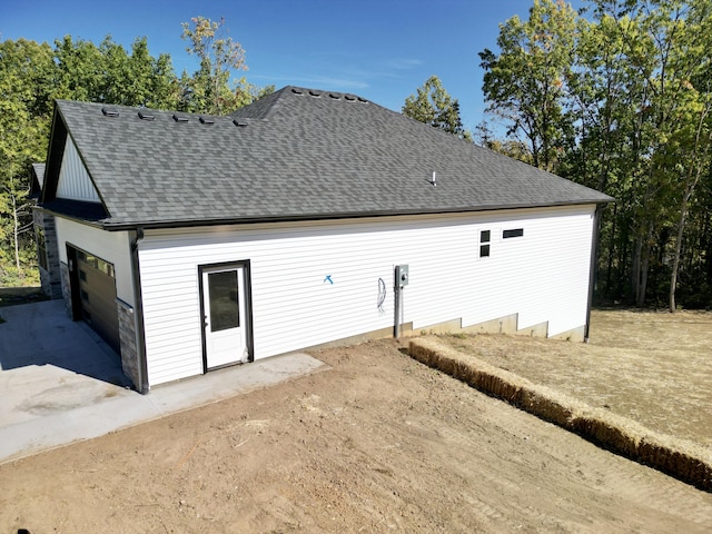 back of property featuring a garage and a shingled roof