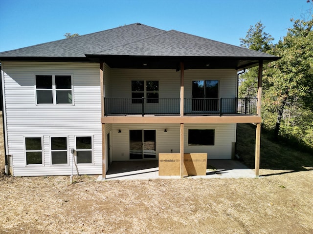 rear view of house with a shingled roof and a patio