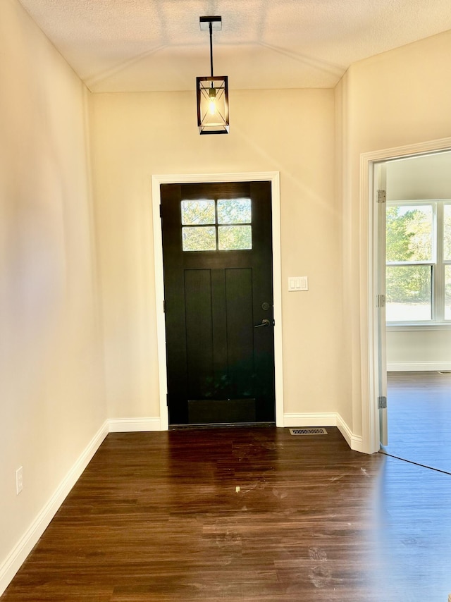 entrance foyer featuring lofted ceiling, dark wood-style floors, baseboards, and a textured ceiling