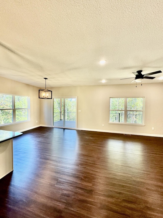 empty room featuring baseboards, dark wood finished floors, and ceiling fan with notable chandelier