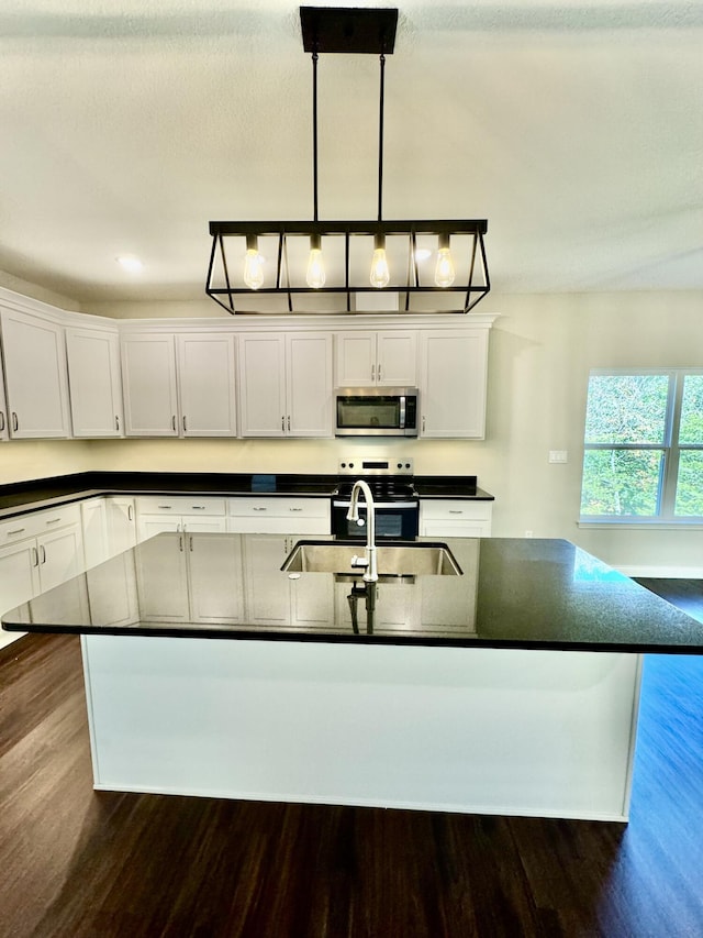 kitchen featuring dark countertops, white cabinetry, appliances with stainless steel finishes, and dark wood-style flooring