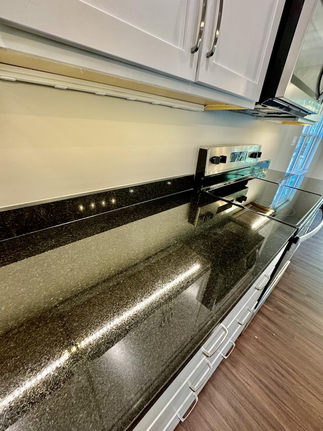 interior details with dark stone counters, white cabinets, and dark wood-style flooring