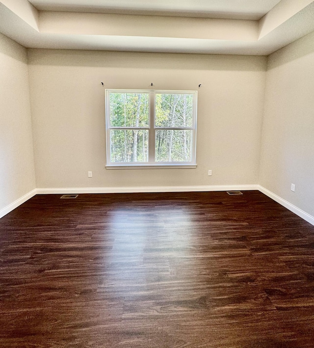 empty room featuring visible vents, baseboards, and wood finished floors