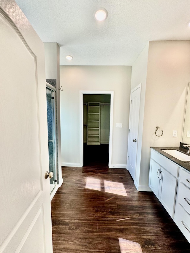 full bath featuring a stall shower, wood finished floors, vanity, and baseboards