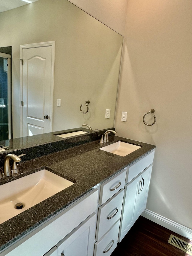 bathroom featuring visible vents, a sink, and wood finished floors