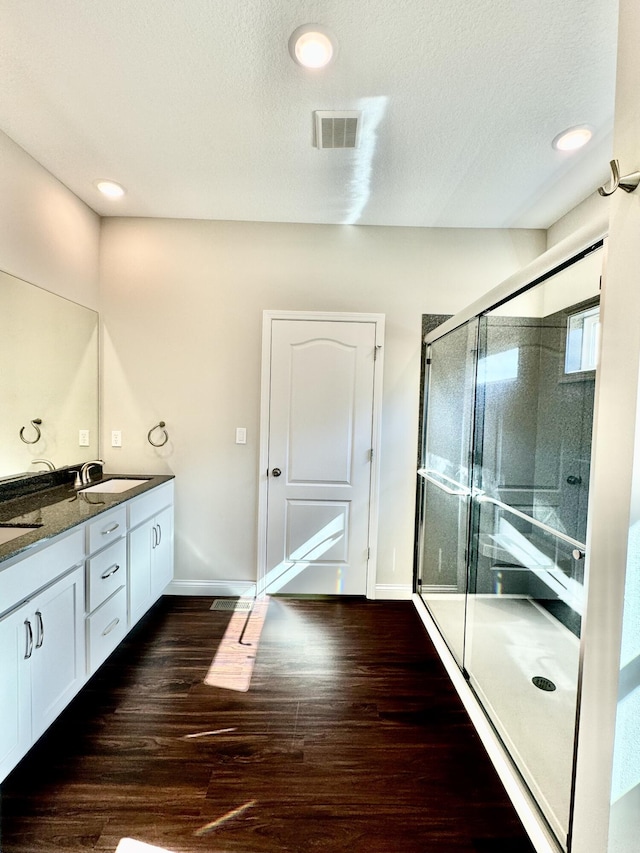 bathroom featuring visible vents, a shower stall, vanity, and wood finished floors