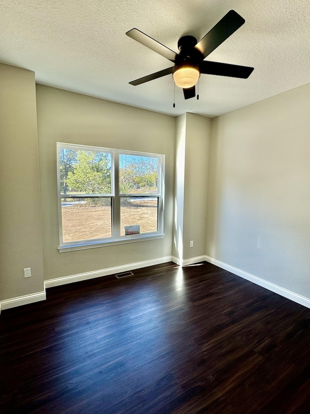 spare room featuring a textured ceiling, wood finished floors, visible vents, and baseboards