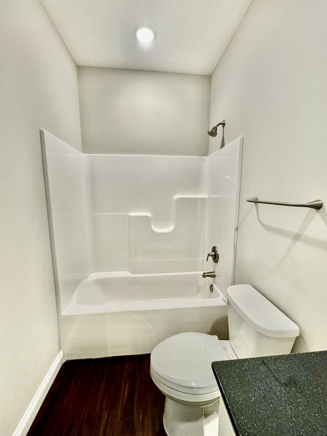 full bath featuring a textured ceiling, toilet, shower / bath combination, wood finished floors, and baseboards