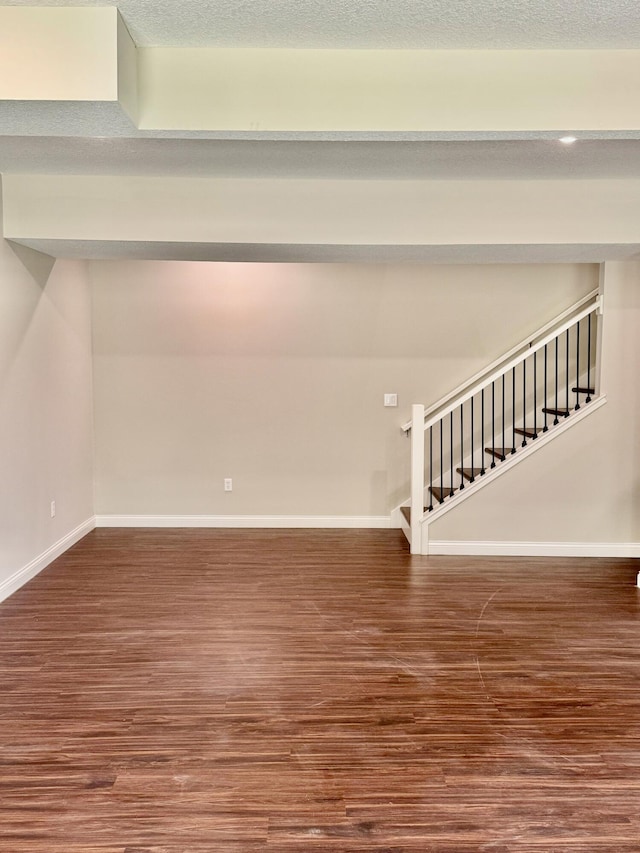 unfurnished room with baseboards, a textured ceiling, stairway, and wood finished floors