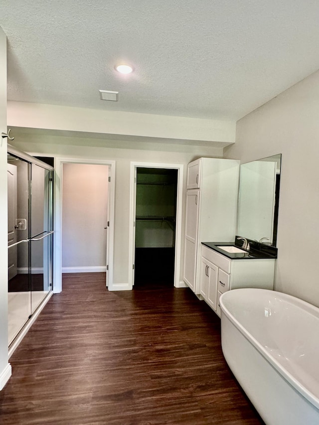 bathroom featuring a stall shower, wood finished floors, a textured ceiling, vanity, and a freestanding tub