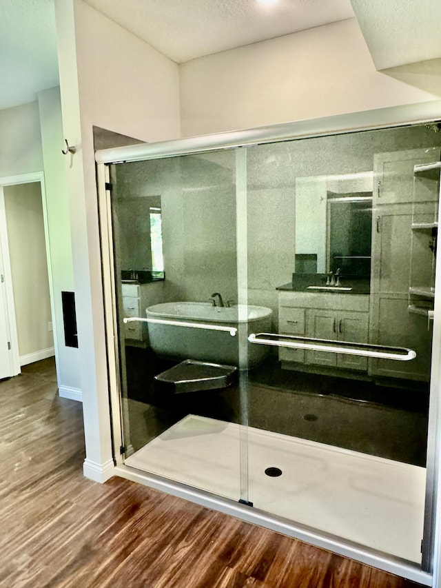 full bathroom featuring a stall shower, vanity, baseboards, and wood finished floors