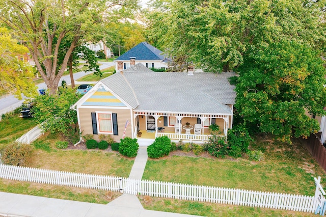 view of front of property featuring a porch, a fenced front yard, a front yard, and a shingled roof