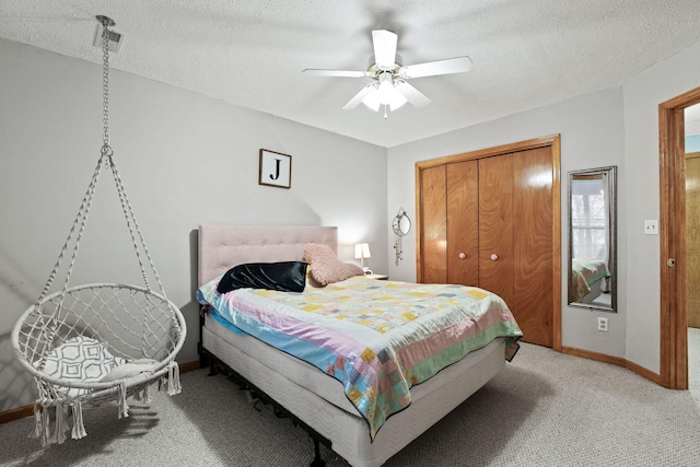 bedroom with a closet, a ceiling fan, light carpet, a textured ceiling, and baseboards