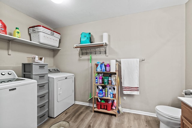 clothes washing area featuring baseboards, laundry area, wood finished floors, and washer and dryer