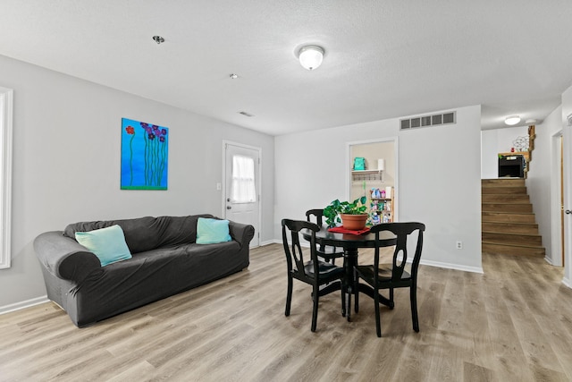 dining area featuring baseboards, stairs, visible vents, and wood finished floors