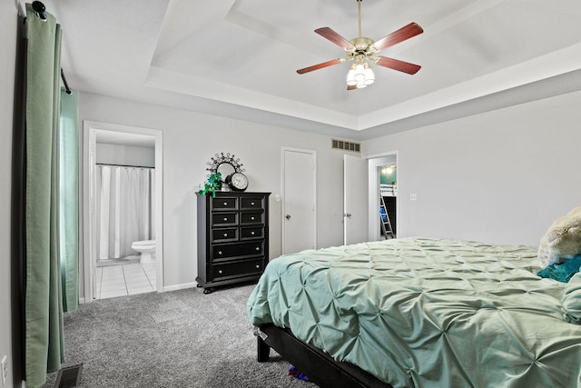 bedroom featuring carpet, visible vents, a tray ceiling, and ensuite bathroom