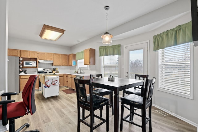 kitchen with light countertops, white microwave, freestanding refrigerator, range with electric cooktop, and under cabinet range hood