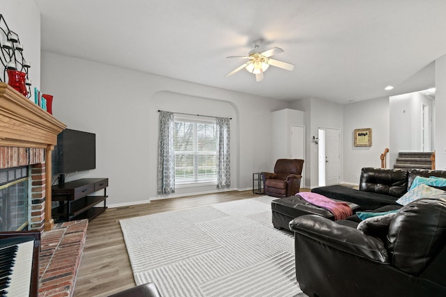 living room with baseboards, a ceiling fan, stairway, wood finished floors, and a fireplace