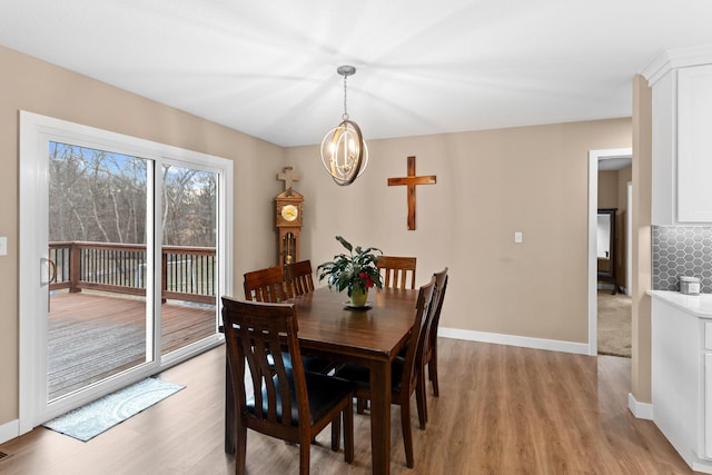 dining area with a notable chandelier, baseboards, and light wood-style floors