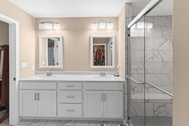 full bathroom with double vanity, marble finish floor, a stall shower, and a sink