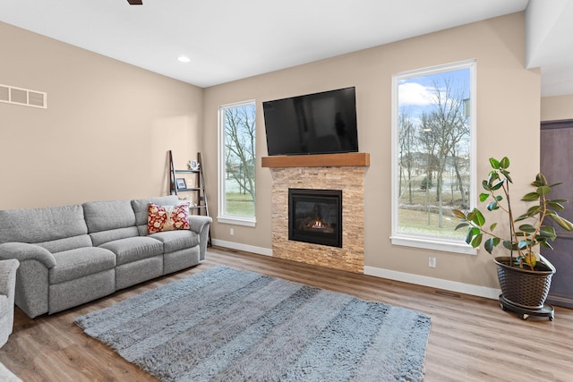 living room featuring plenty of natural light, wood finished floors, visible vents, and baseboards