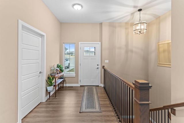 entryway featuring an inviting chandelier, wood finished floors, and baseboards