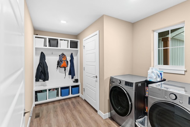 laundry room with washing machine and clothes dryer, visible vents, light wood finished floors, baseboards, and laundry area