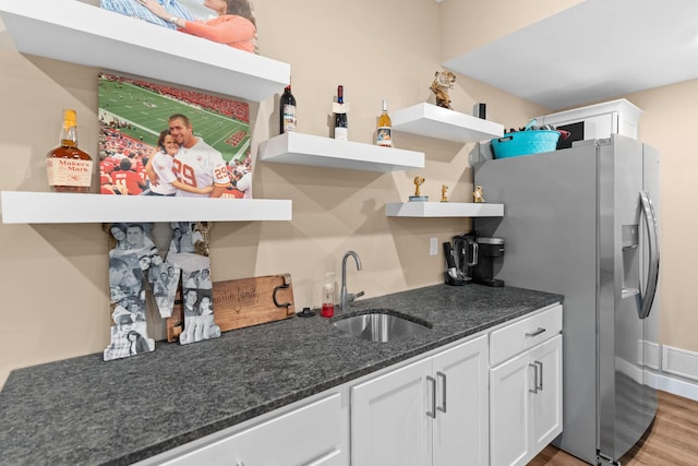 kitchen with stainless steel refrigerator with ice dispenser, open shelves, a sink, white cabinets, and light wood finished floors