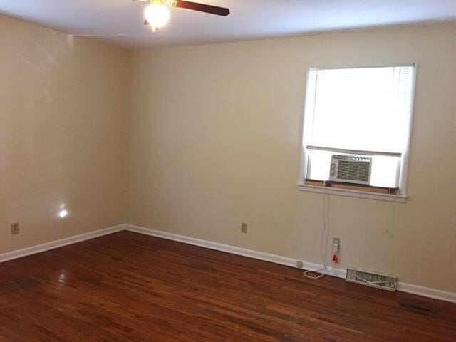 spare room featuring visible vents, baseboards, and wood finished floors