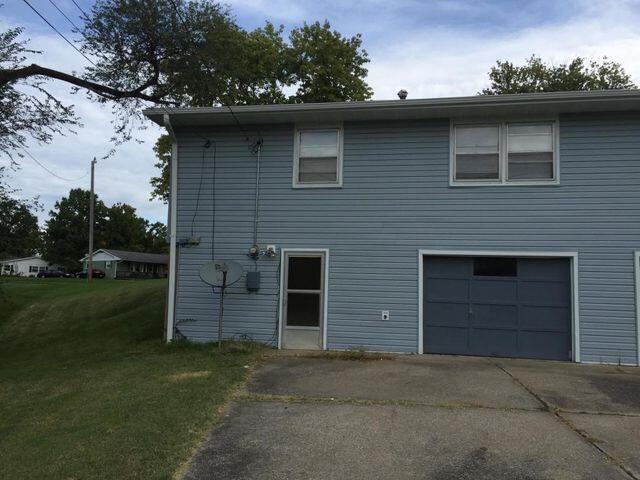 rear view of house featuring a lawn and a garage