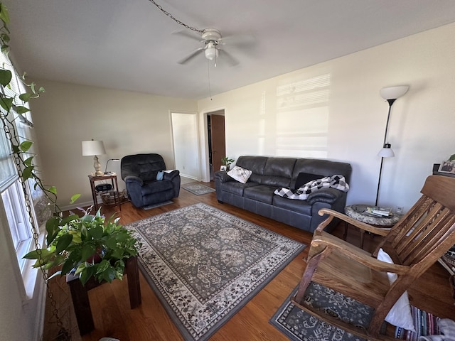 living area with baseboards, ceiling fan, and wood finished floors