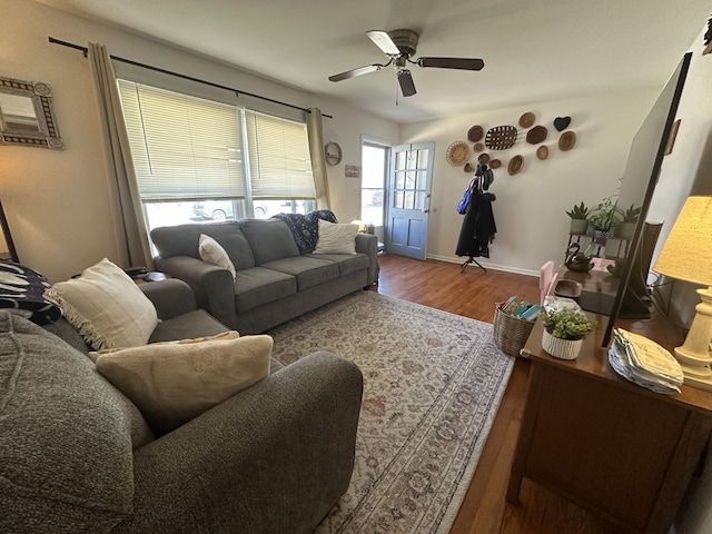 living room with ceiling fan, baseboards, and wood finished floors