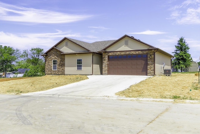 view of front of house with a garage, cooling unit, stone siding, and driveway