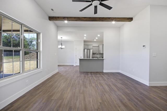 unfurnished living room featuring dark wood-style floors, beamed ceiling, a wealth of natural light, and baseboards