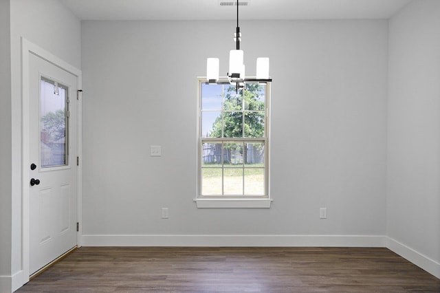 unfurnished dining area with a chandelier, dark wood-type flooring, visible vents, and baseboards